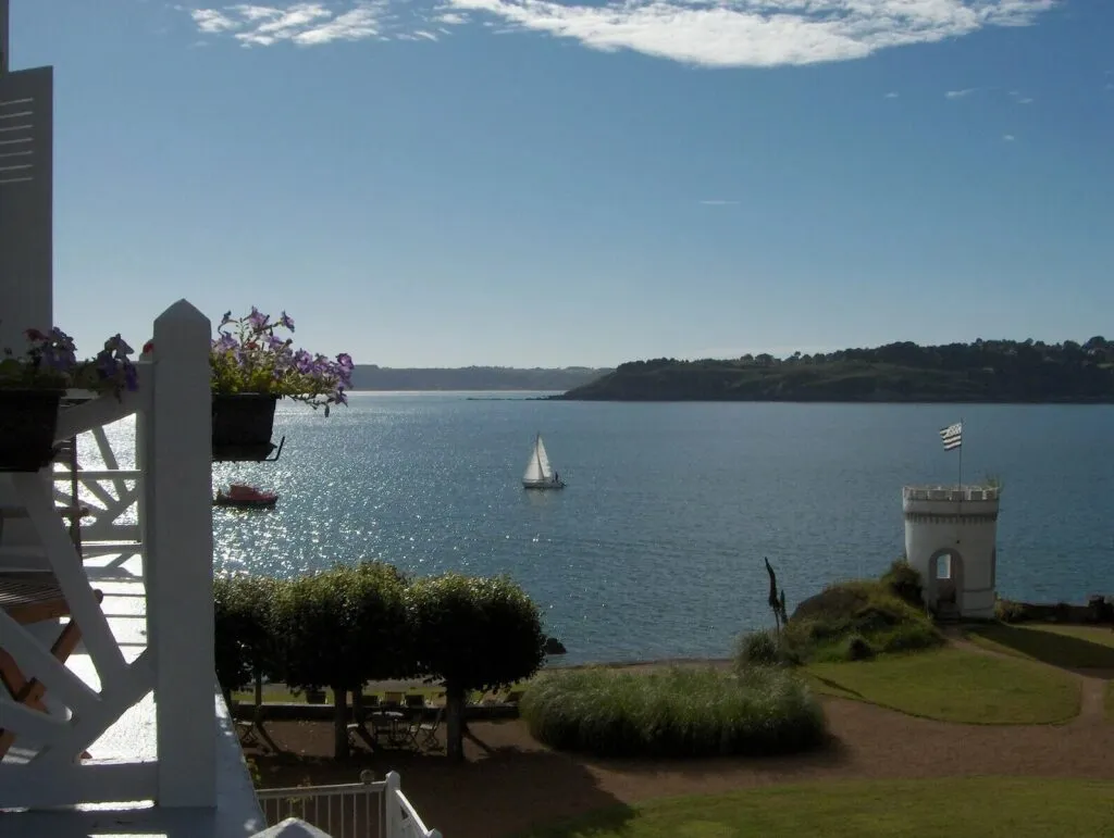 Vue sur la mer et la côte bretonne depuis le Grand Hôtel des Bains à Locquirec, avec un voilier et une tourelle en bord de mer