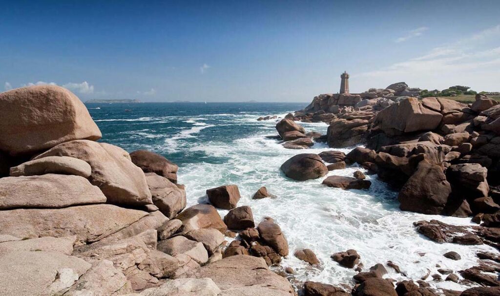 Spectacular view of the pink granite coast with lighthouse and waves, near Locquirec in Brittany