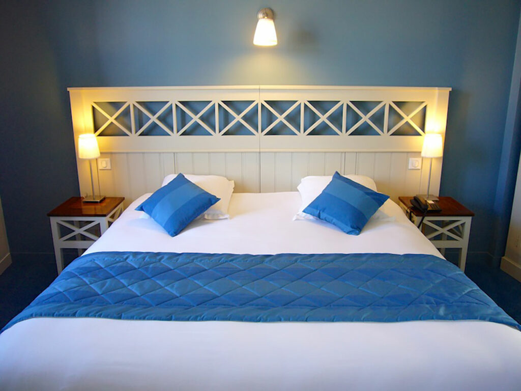 Comfortable blue-toned room at the Relais de Brocéliande with large double bed and warm, home-like decor