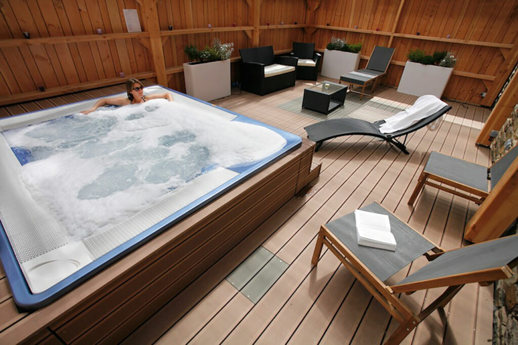 Spa area with wooden Jacuzzi and deckchairs at the Relais de Brocéliande, wellness hotel in Paimpont