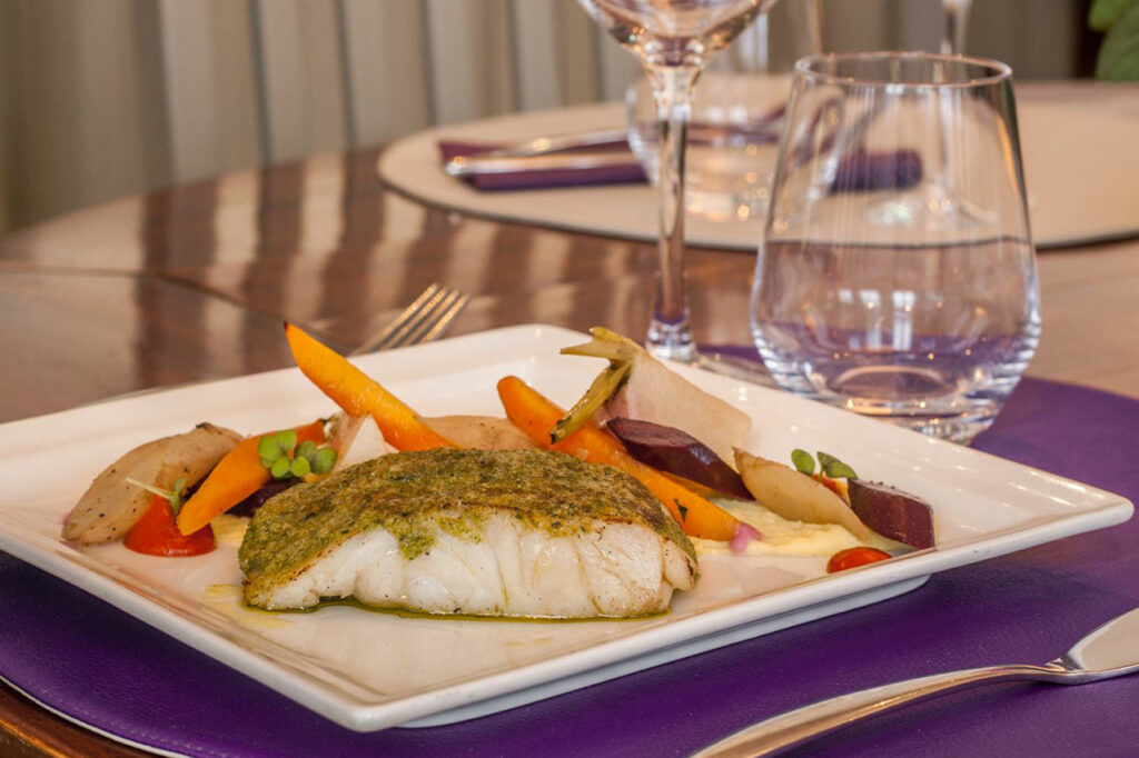 Gourmet plate with colorful fish and vegetables at the Relais de Brocéliande restaurant in Paimpont