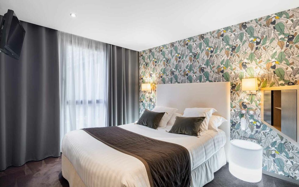Chambre moderne et élégante de l’Hôtel Edgar à Saint-Brieuc, avec un papier peint végétal et une lumière douce