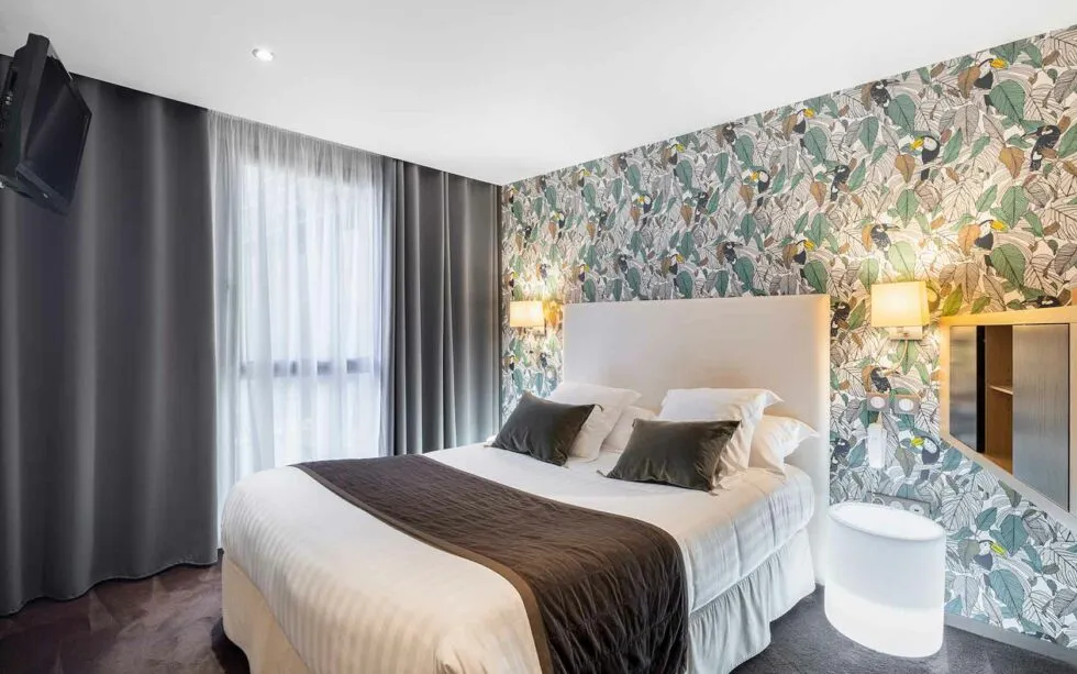 Chambre moderne et élégante de l’Hôtel Edgar à Saint-Brieuc, avec un papier peint végétal et une lumière douce