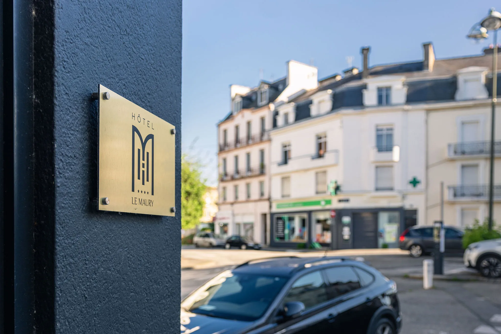 Plaque en laiton de l’Hôtel Le Maury à Vannes, fixée sur la façade, avec en arrière-plan une rue du centre-ville et des immeubles anciens