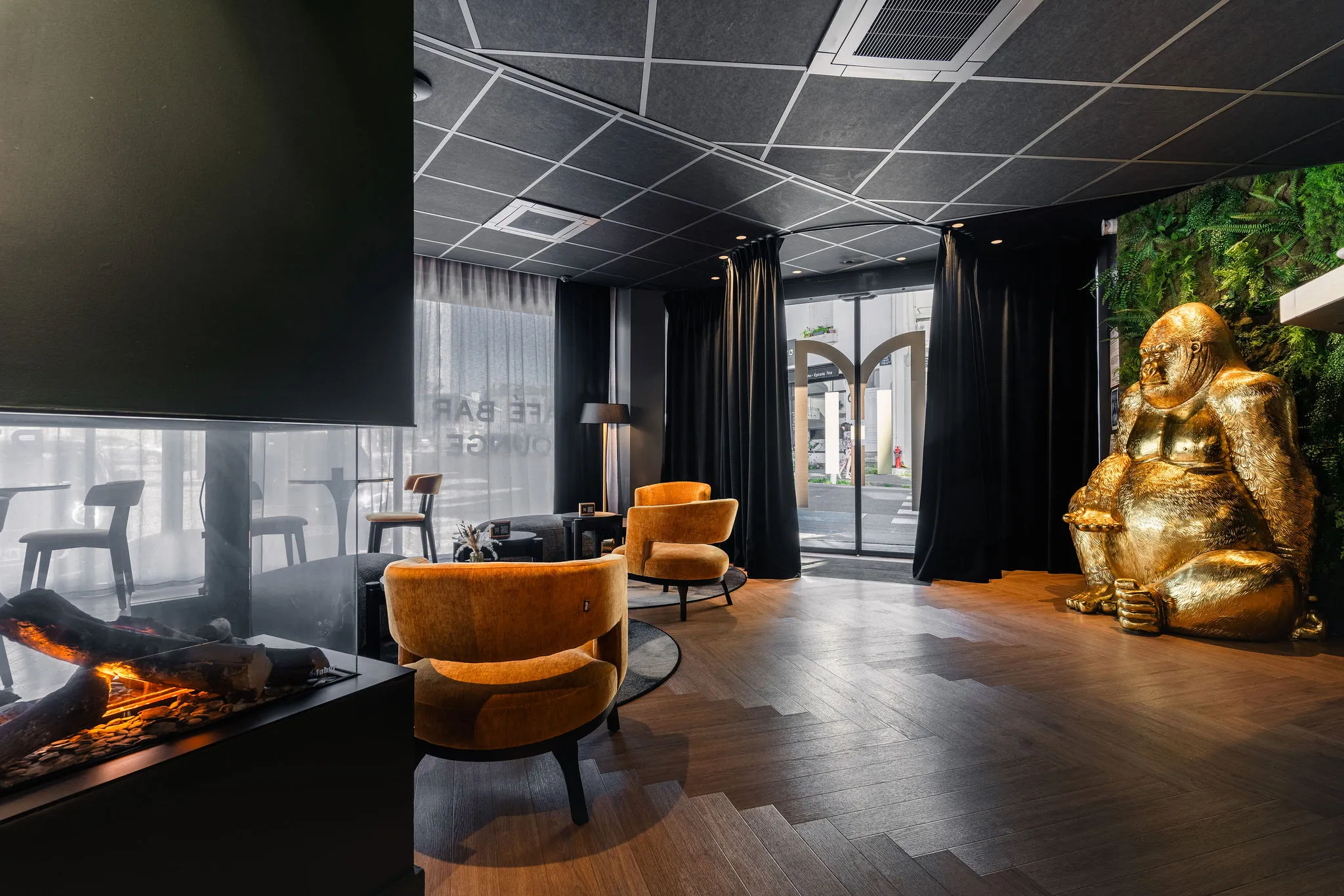 Lobby design de l’Hôtel Le Maury à Vannes avec fauteuils orange, cheminée moderne et statue dorée originale