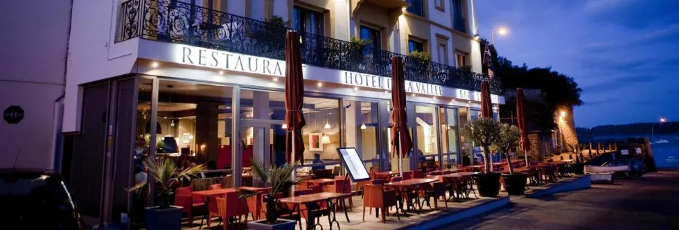Façade de l’Hôtel de la Vallée à Dinard en soirée avec terrasse du restaurant en bord de mer