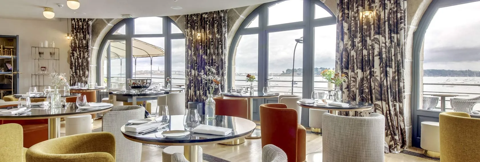 Salle du restaurant du Castelbrac à Dinard avec vue panoramique sur la mer et les voilures de Saint-Malo à l’horizon