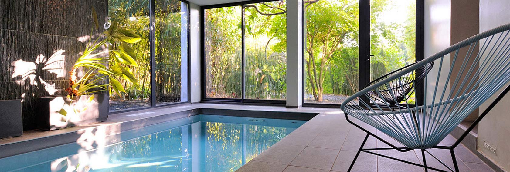 Espace détente de l’hôtel Ty Mad à Douarnenez avec piscine intérieure et vue sur un jardin verdoyant
