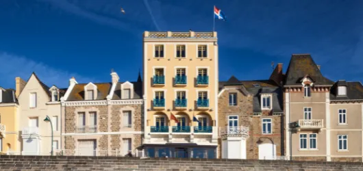 Façade élégante de l’hôtel Les Ambassadeurs à Saint-Malo, face à la mer et bordée de villas typiques de la côte bretonne.