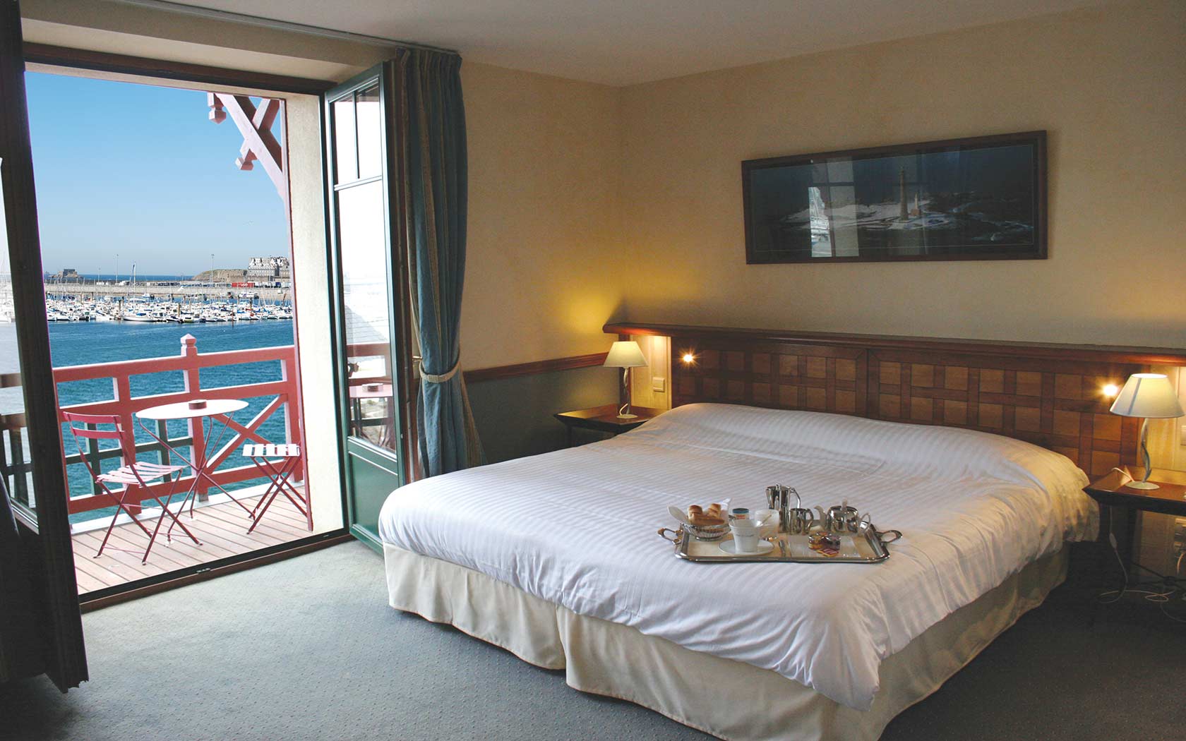 Elegant room at Cunningham Manor with double bed, breakfast tray and harbor view from balcony.