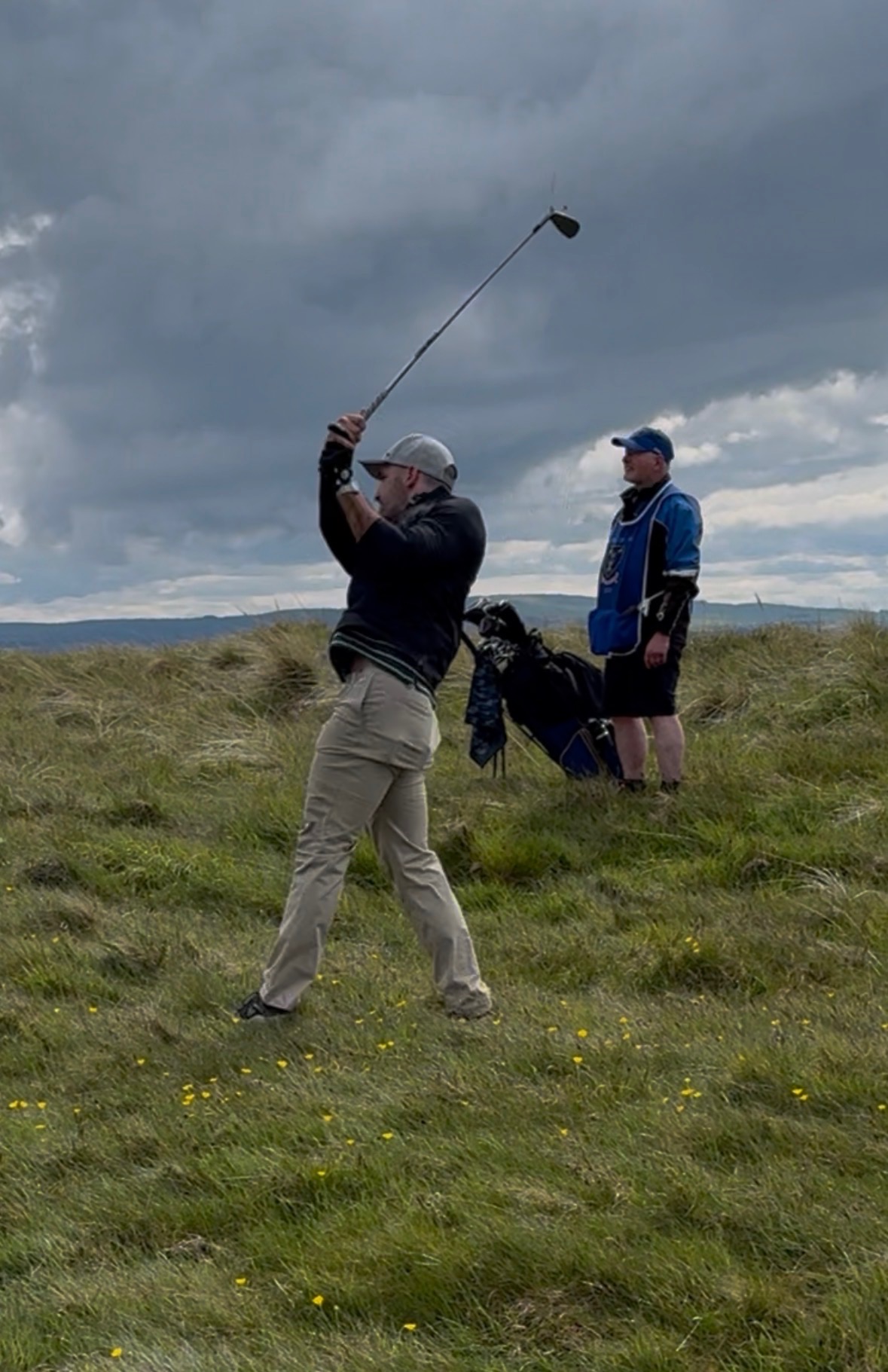 Golfer over 50 mid-swing on a windswept course during golf performance training with Essential Strength Pittsburgh