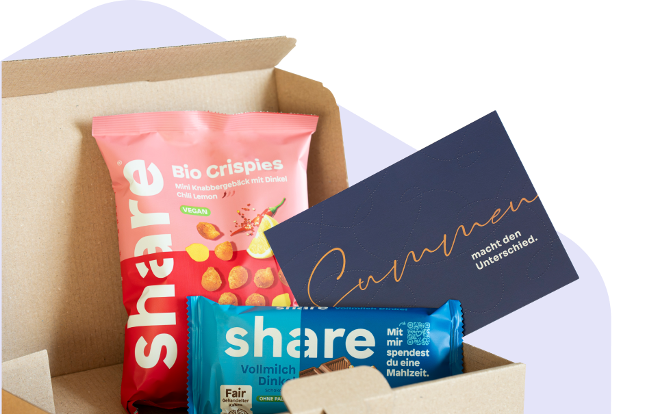 Geöffnete Schachtel mit pinkem Bio-Crispies Snack, blauem Schokoladenriegel und einer dunkelblauen Karte mit goldener Schrift.