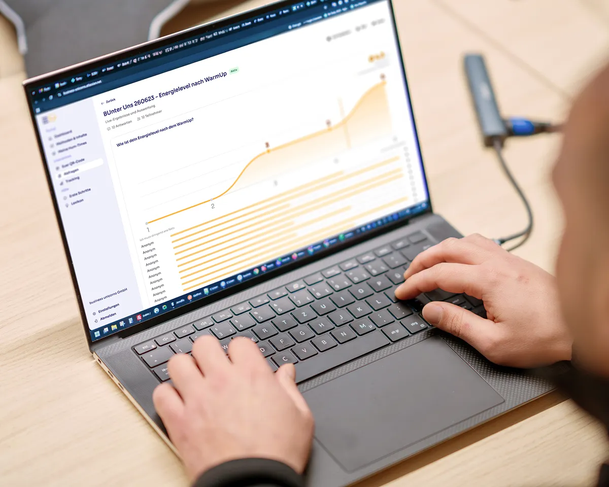 Person tippt auf einem Laptop, der eine Grafik Energielevel nach WarmUp zeigt, inklusive eines Kurvendiagramms und Antworten von anonymen Teilnehmern.