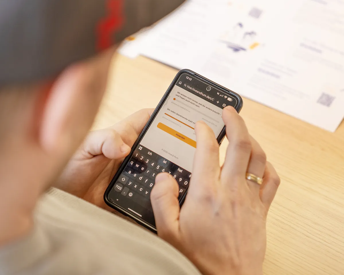 Person tippt auf einem Smartphone mit geöffneter Webseite zur Eingabe von Daten in deutscher Sprache.