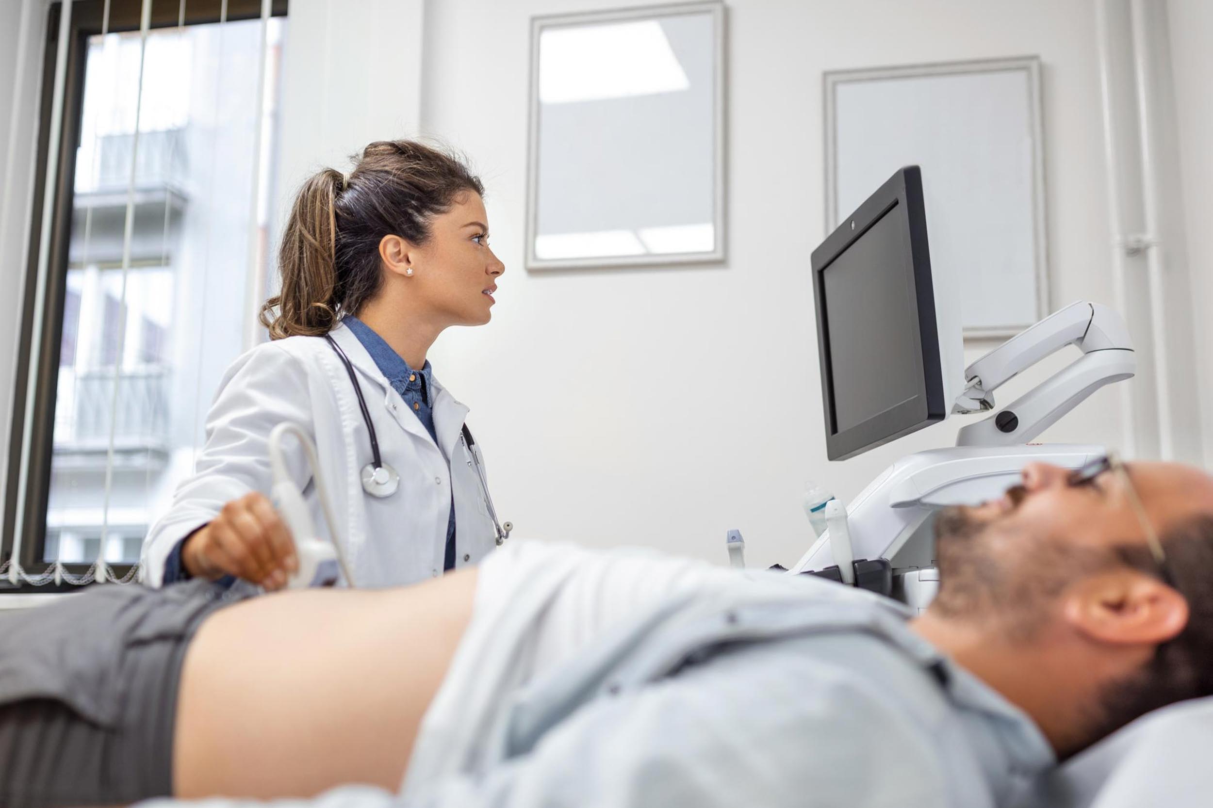 Doctor performing an ultrasound on a patient lying on an exam table.
