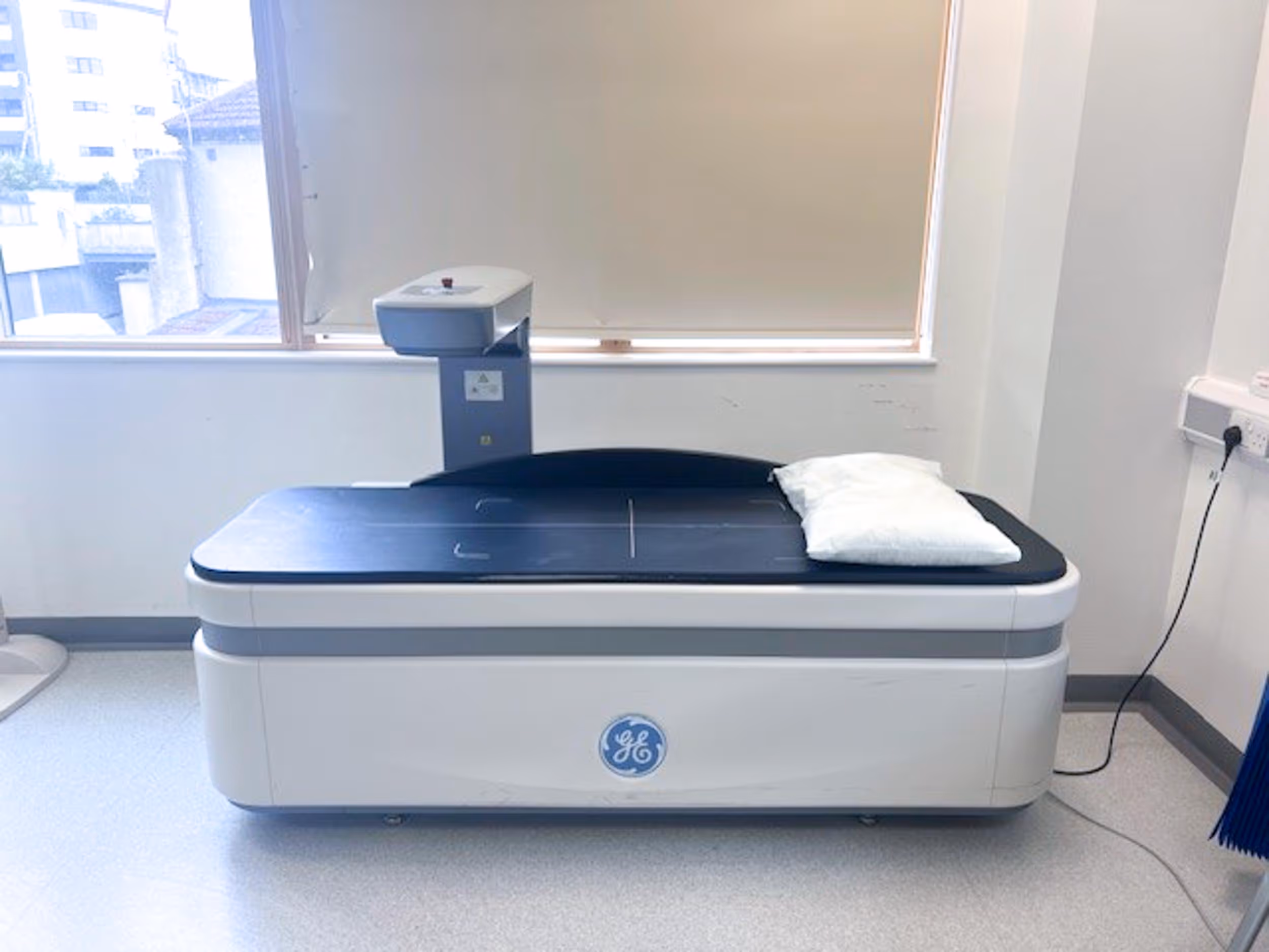 Medical imaging machine in a hospital room with a pillow on the examination table.