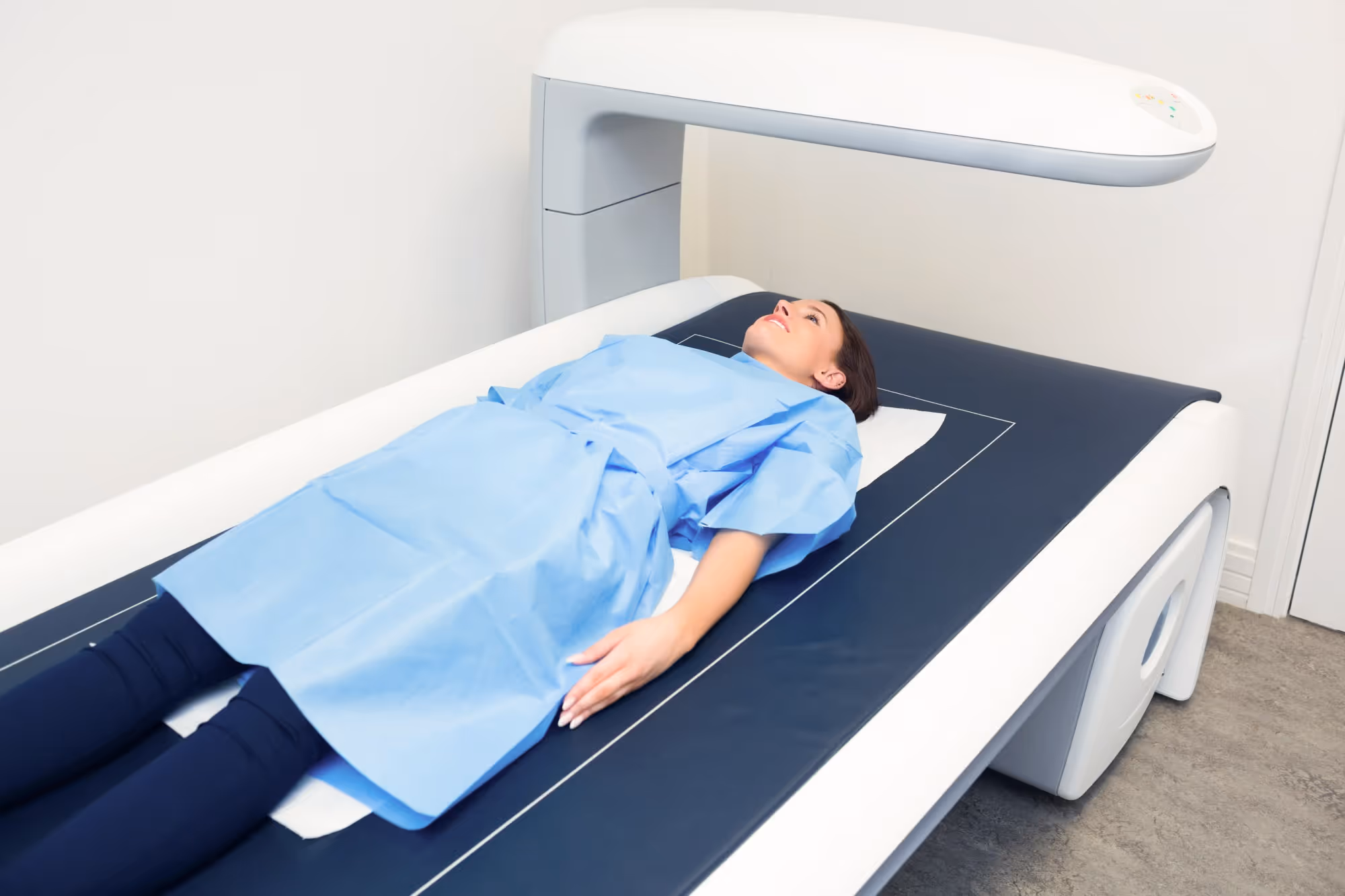 A person in a medical gown is lying on a table, undergoing a medical scan.