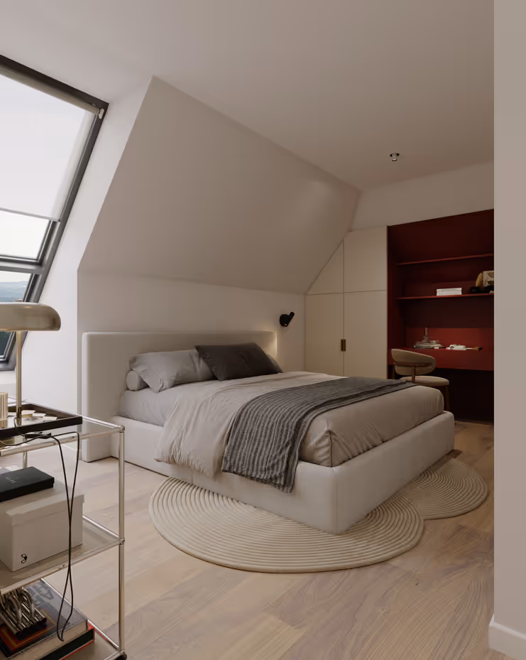 Modernes Schlafzimmer unter einer Dachschräge mit beigem Polsterbett, grauer Bettdecke und zwei Kissen, rundem Teppich, großem Fenster und Arbeitsbereich mit rotem Regal und Stuhl.