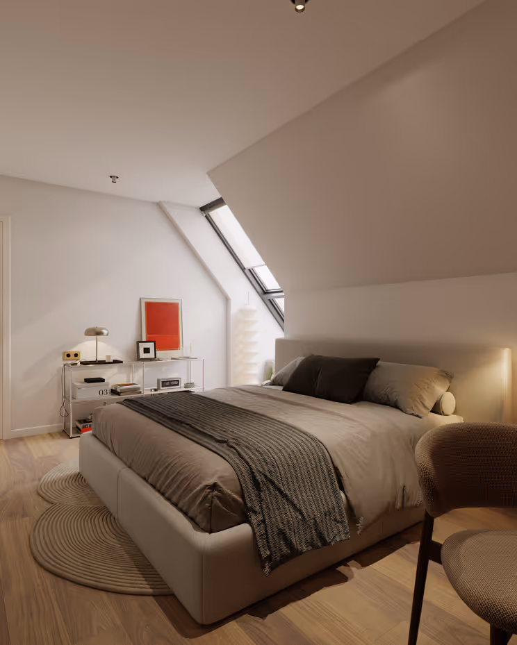 Modernes Schlafzimmer mit einem beige gepolsterten Bett, brauner Bettdecke und zwei Kissen, Holzboden, rundem Teppich, Stuhl und einer Glasablage mit Dekoartikeln unter einem Dachschrägenfenster.