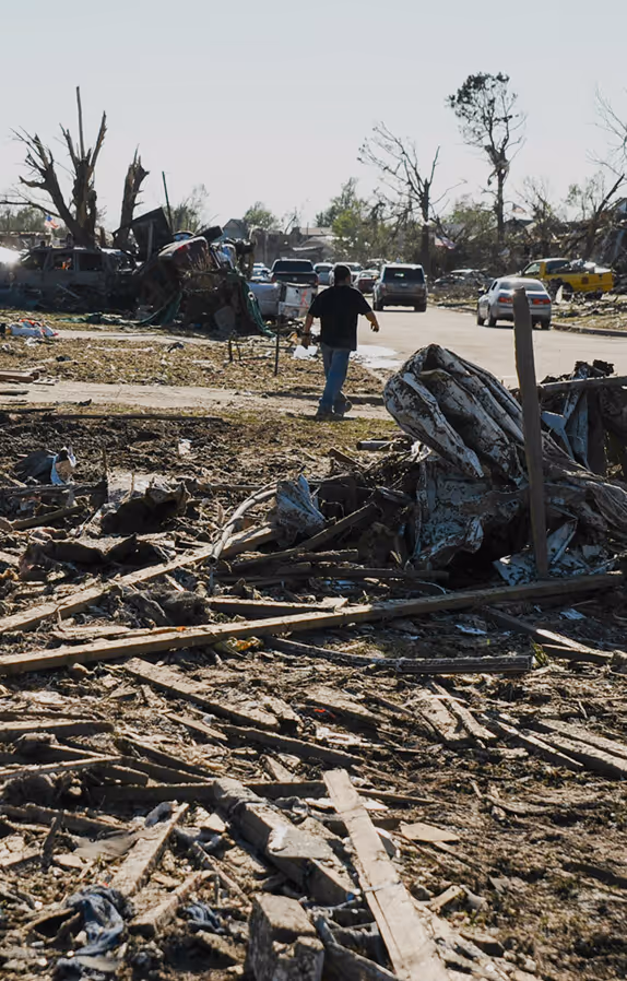 A man walking through rubble after a destructive event