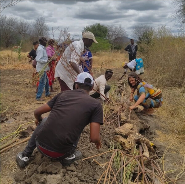 A group of people working together on the ground clearing the soil
