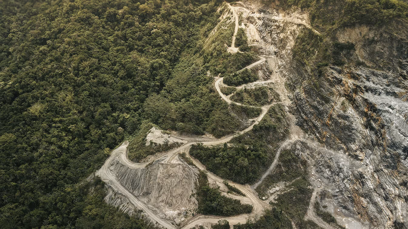 An aerial view showing green land on one side and deforestation on the other