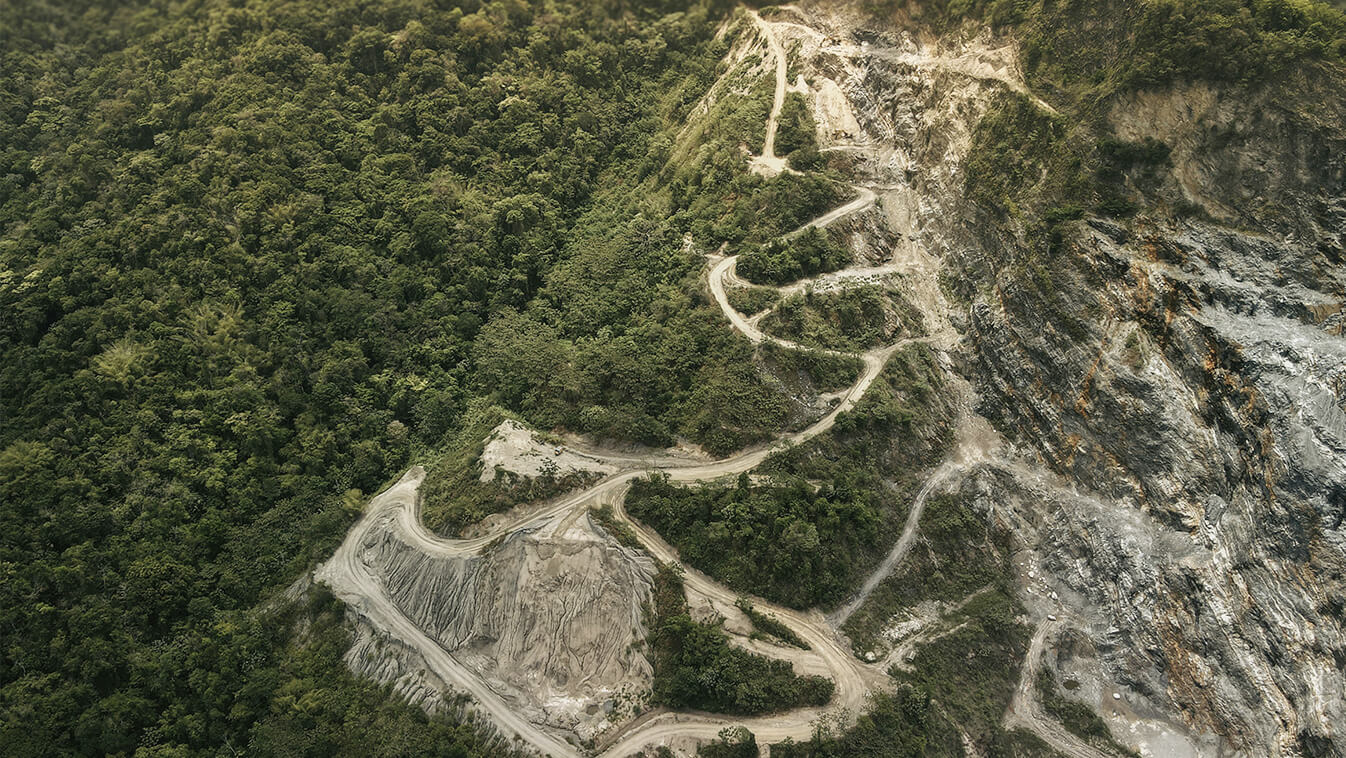 An aerial view showing green land on one side and deforestation on the other