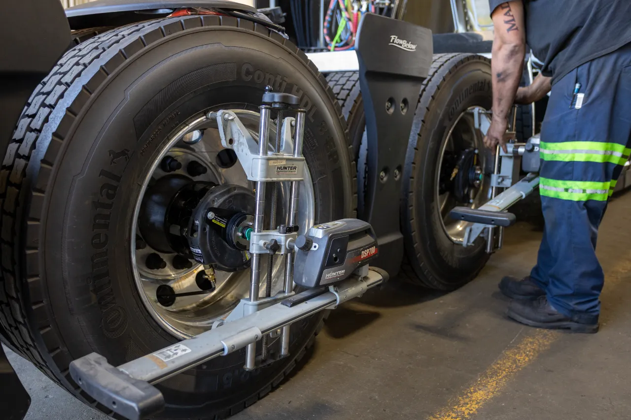Technician performing misalignment check on rear axles using Hunter equipment on a heavy-duty truck.