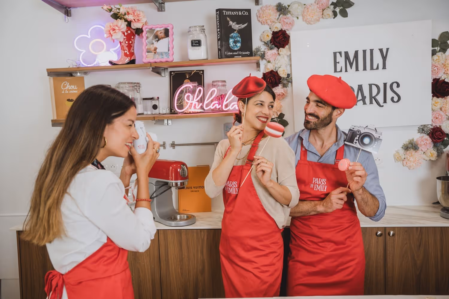 Macaron making guest taking a picture of another 2 guests with the macaron making class props