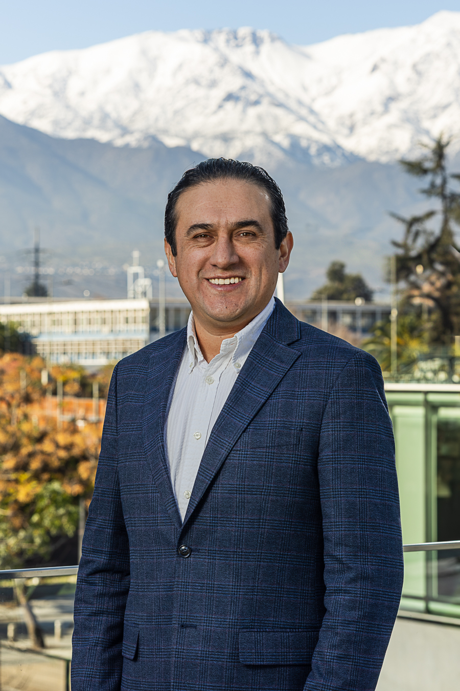 Retrato de Alberto Castañeda con fondo de ciudad y montañas