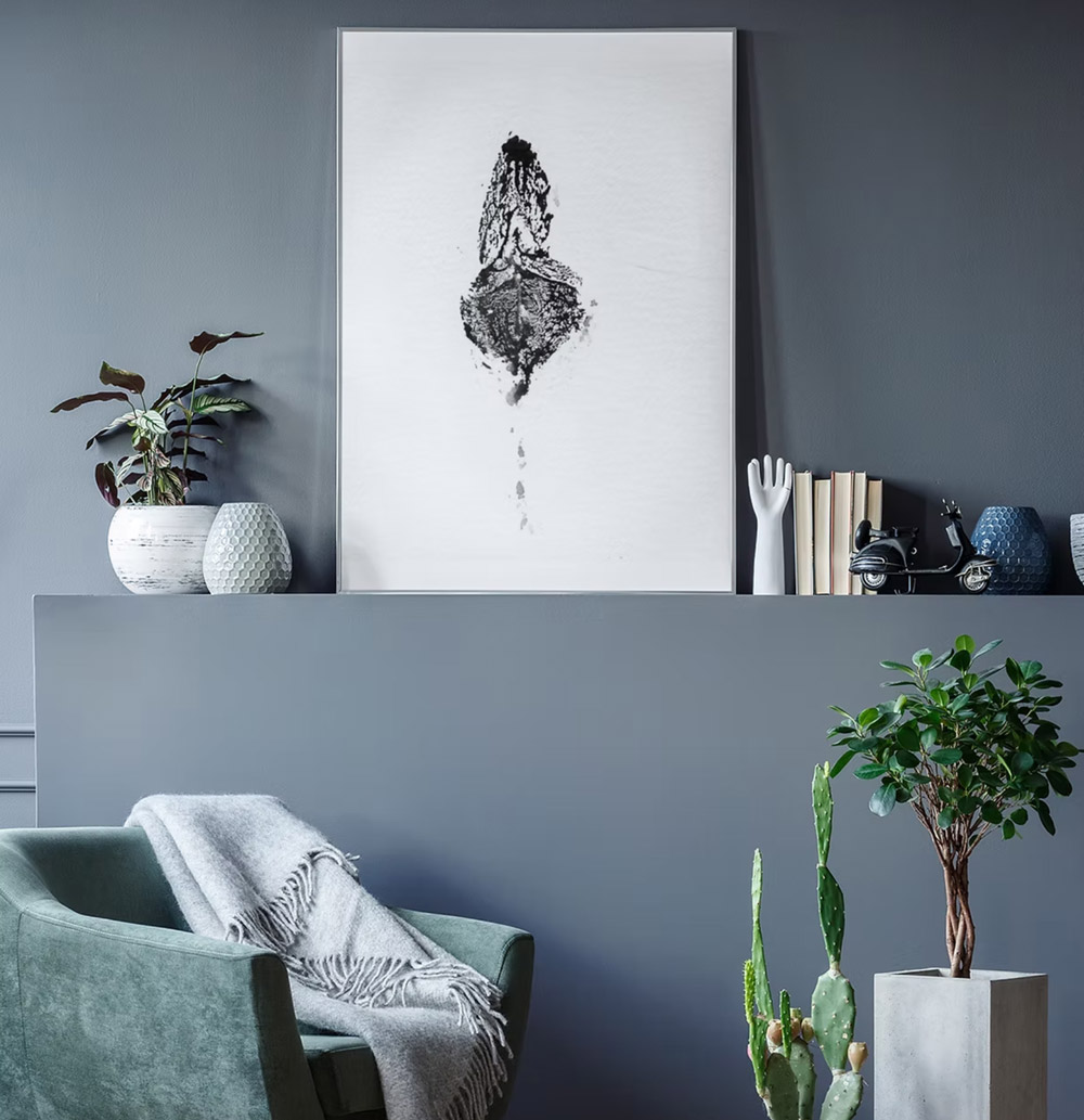 Elegant black yoni print on a white canvas displayed on a shelf in a modern blue interior.