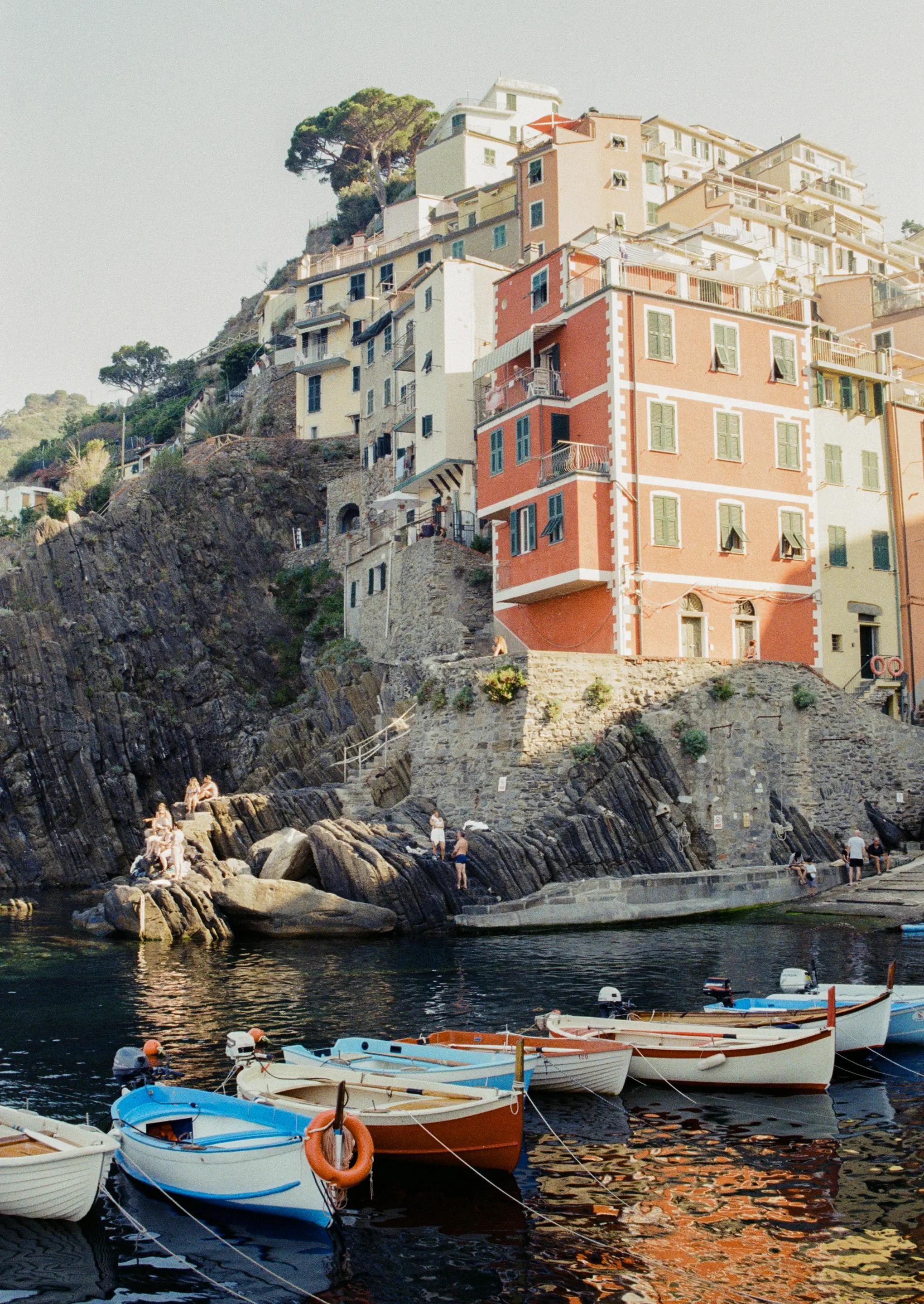 Small boats docked alongside one another under a historic French landscape and building.