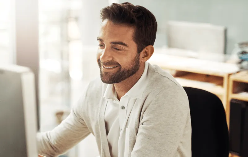 A man sitting in front of a computer smiling.