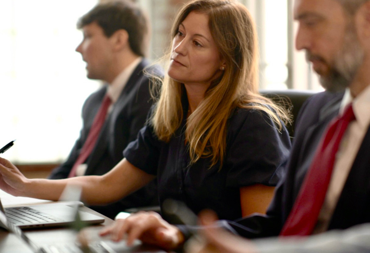 Lauren Lambright from Smolen & Roytman working at laptop in a meeting room with natural light.