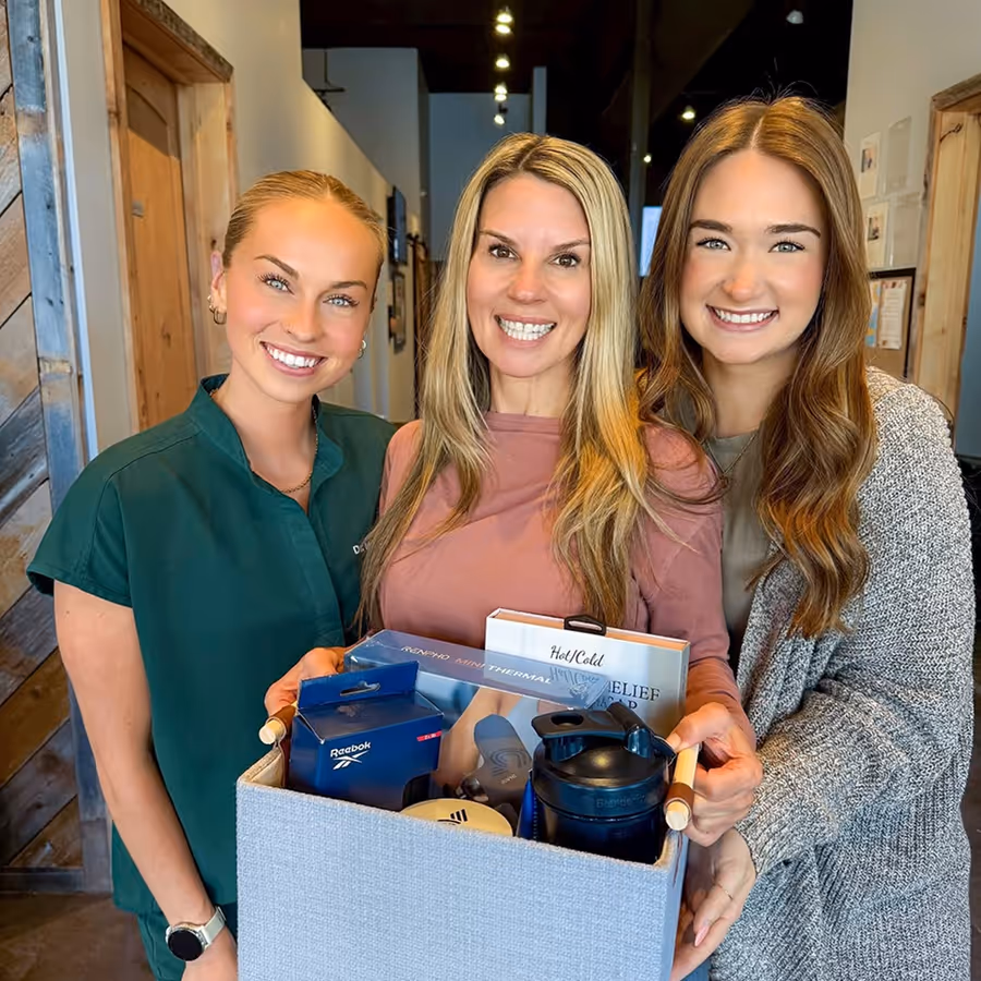 Three women smiling and holding a box of coffee.