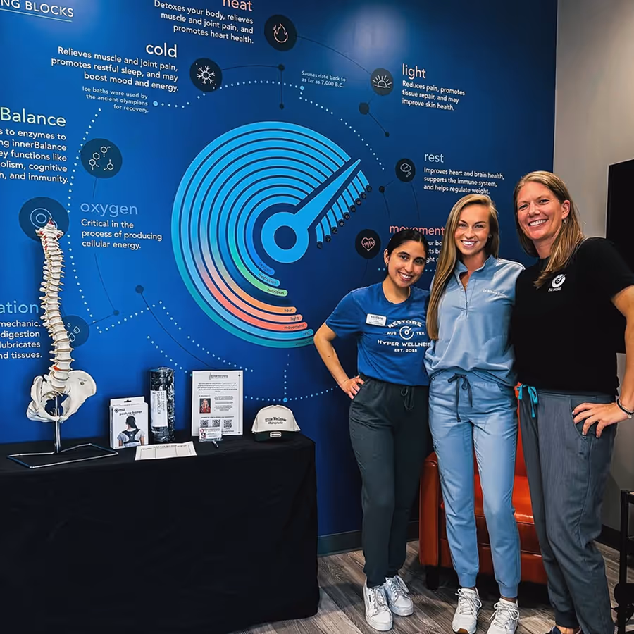 Three women standing in front of a wall with a spine diagram.