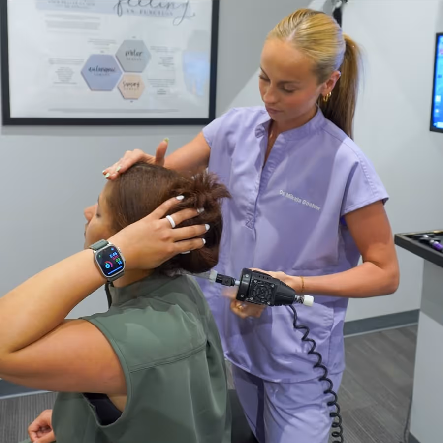 A woman is getting her hair blow dried by another woman.