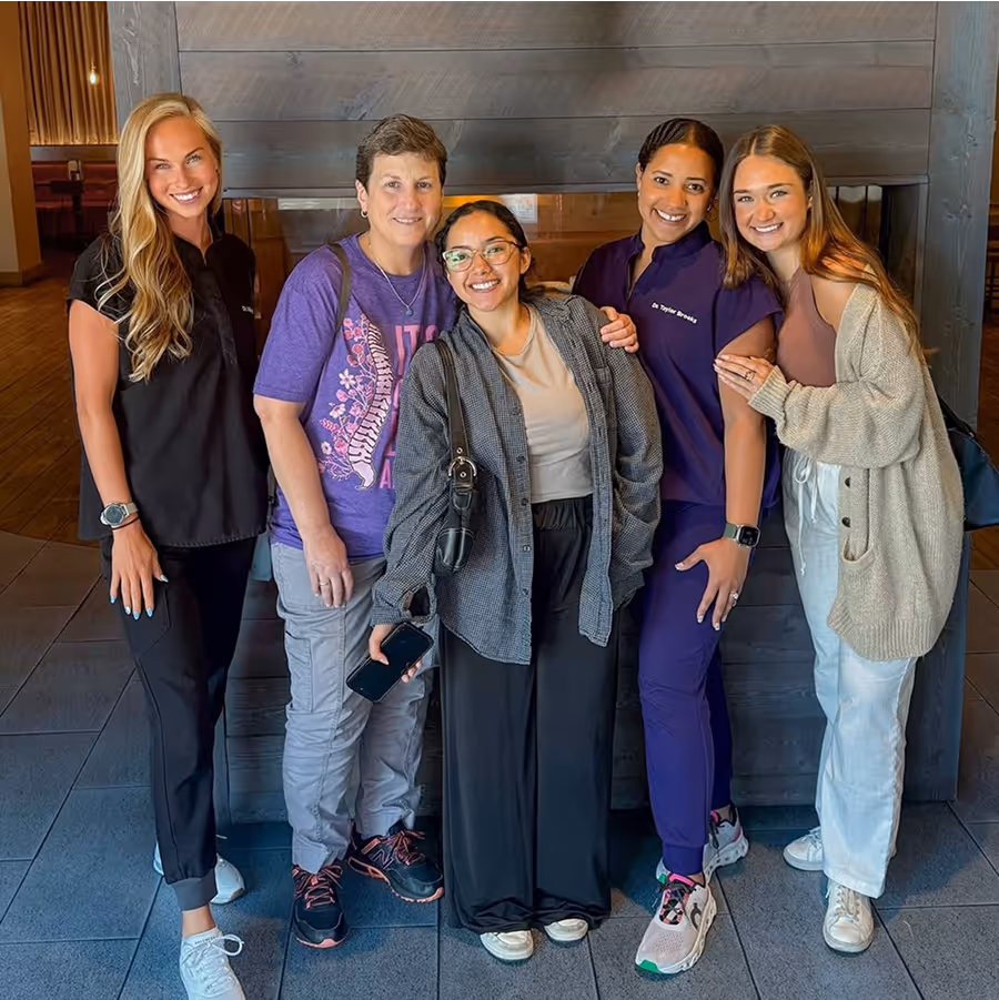 A group of women posing for a picture in front of a fireplace.