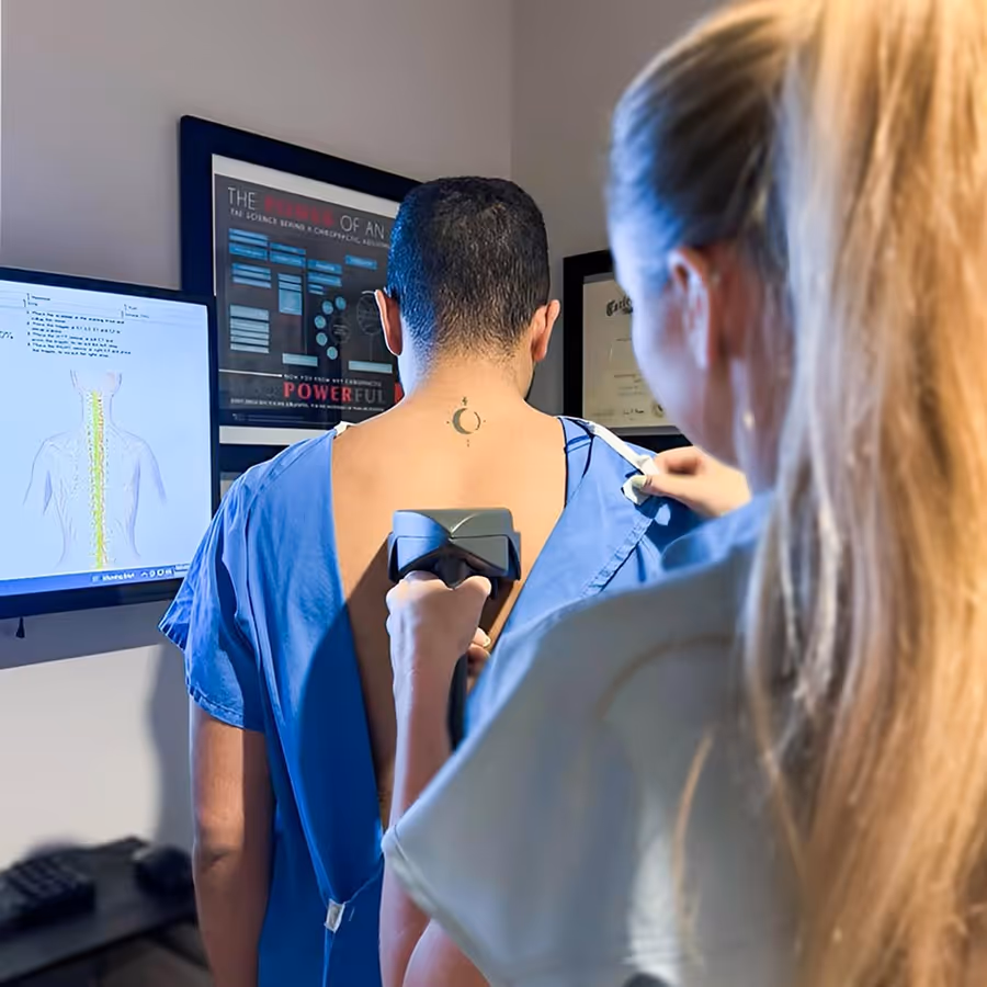 A woman is measuring a man's back with a device.