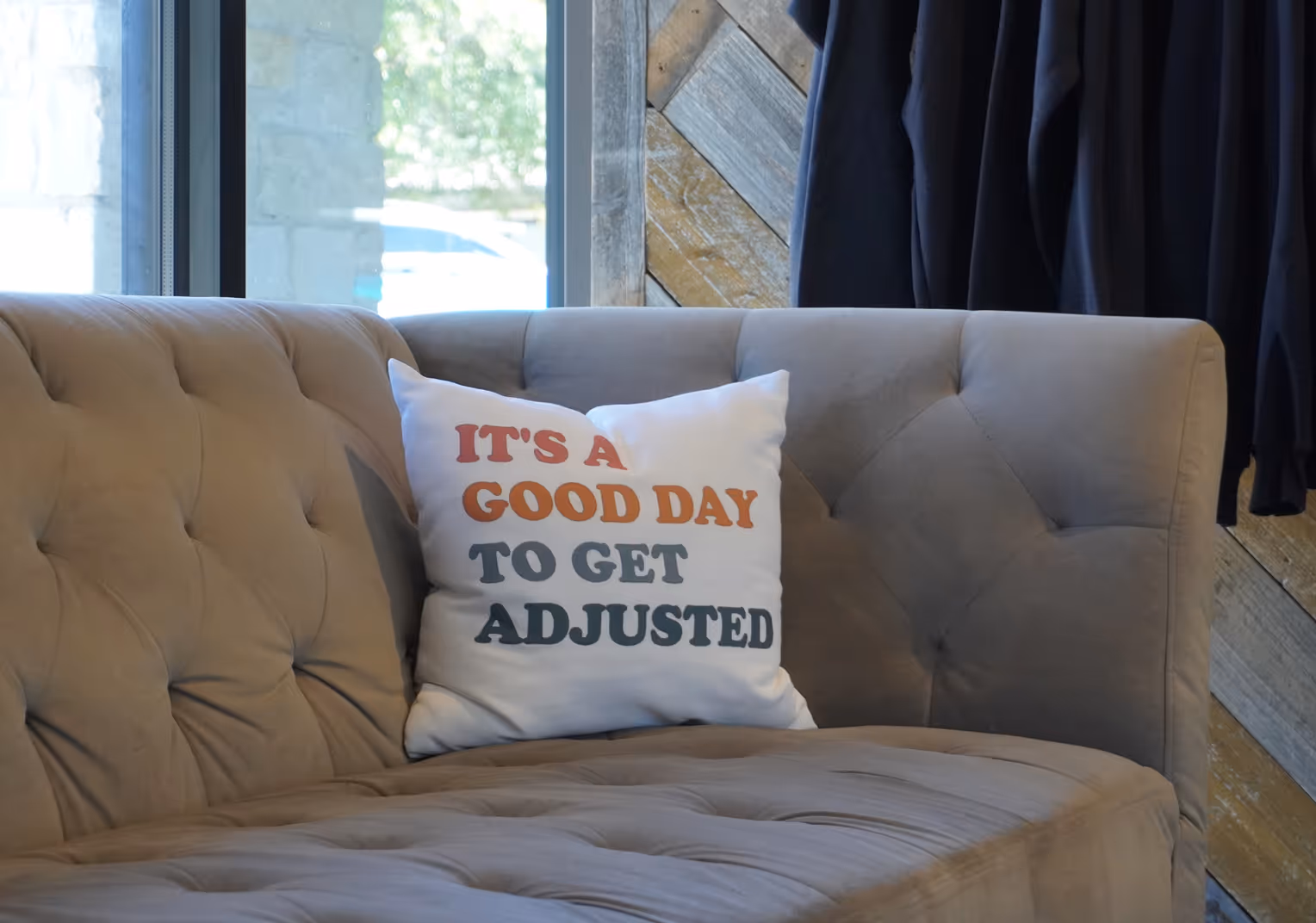A couch with a pillow that says "It's a good day to get adjusted".