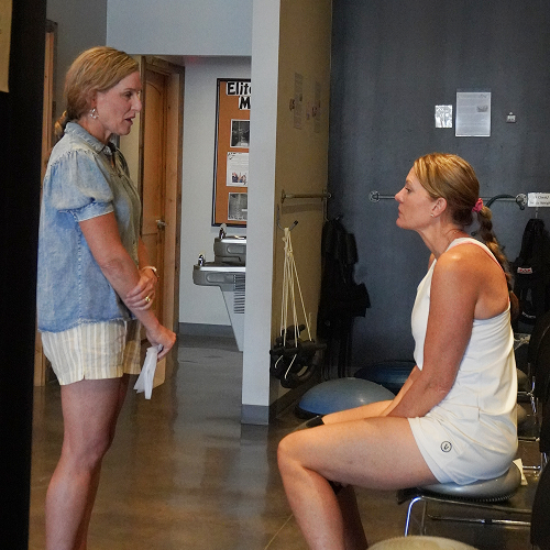 Chiropractor consulting with a patient seated on a stability ball during a rehab session at Elite Wellness Chiropractic