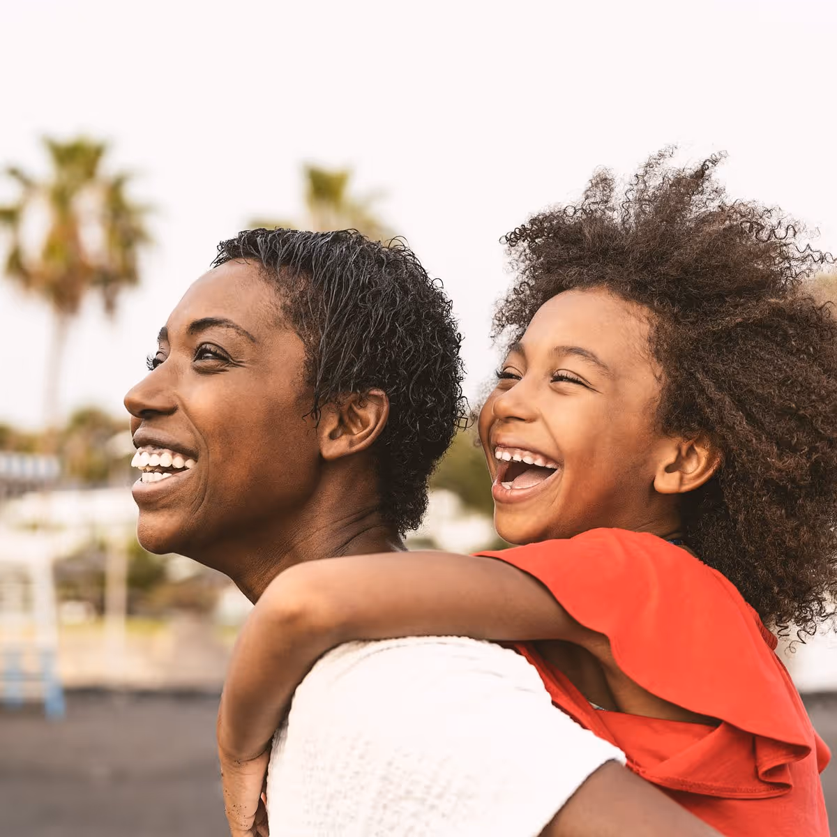 Happiness that lasts beyond move-in day. Smiling parent giving their child a piggyback ride outdoors.