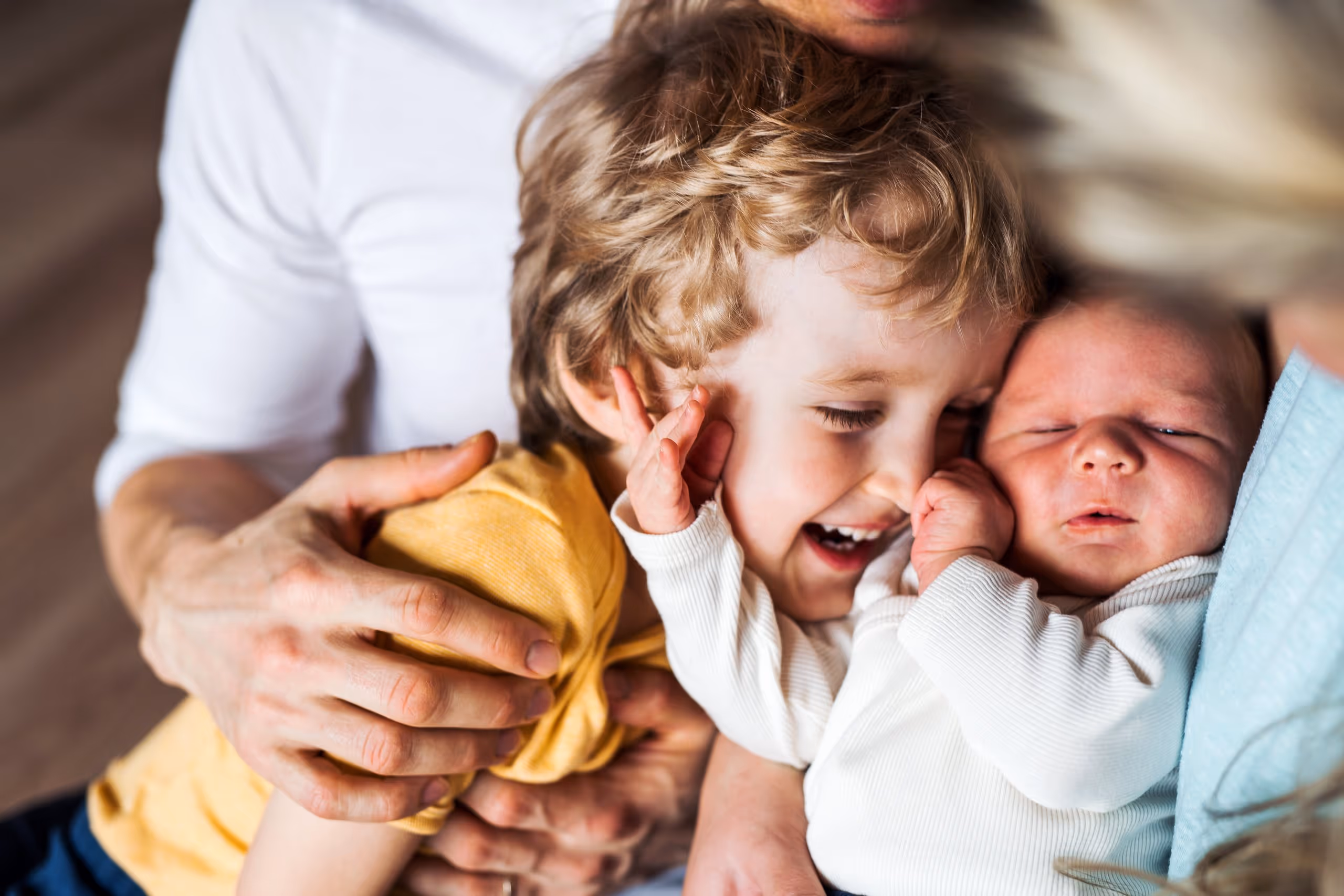 Every home starts with care. Parent cradling a newborn baby in a softly lit room.