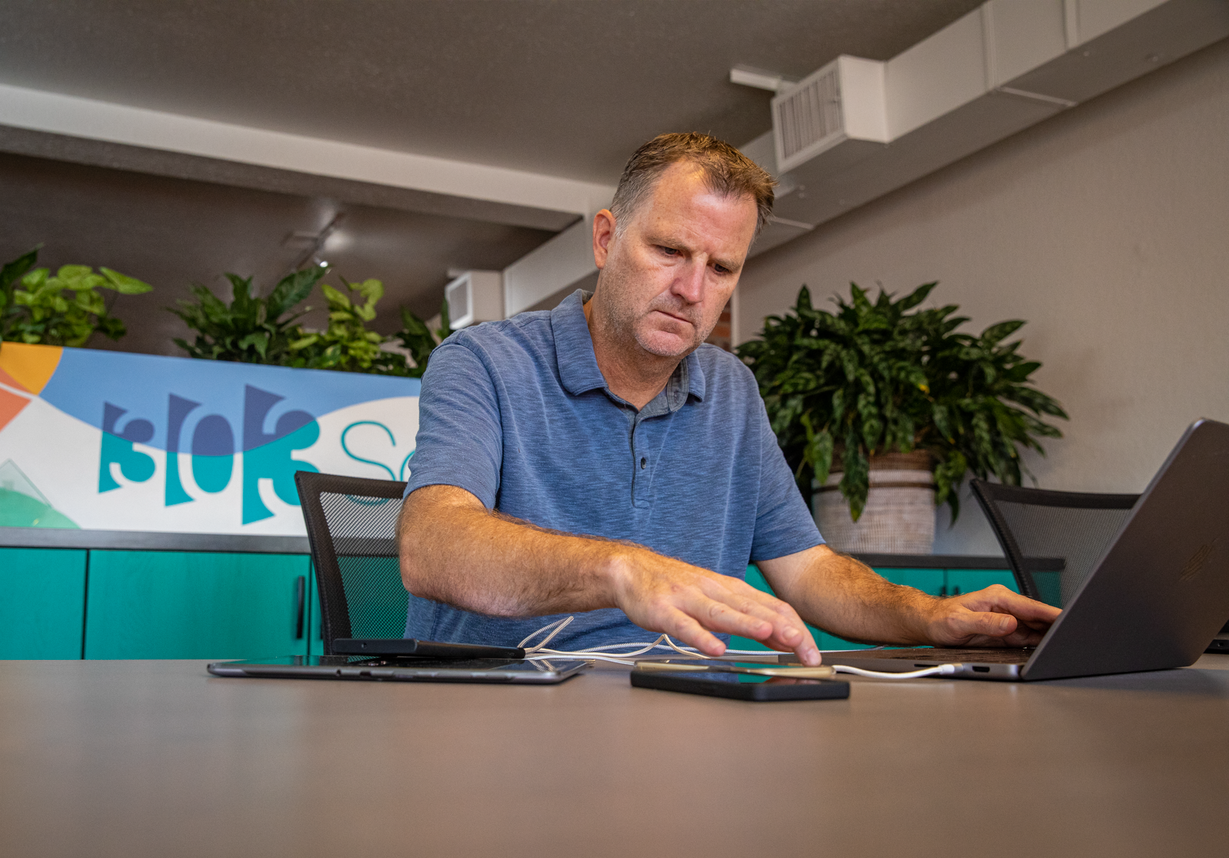 303 Software iOS developer testing a mobile app on an iPhone while working on a laptop in the Denver office.