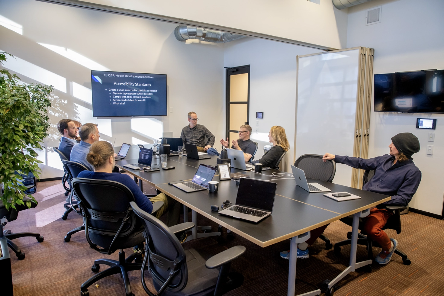 The 303 Software team in a conference room reviewing a mobile development roadmap on screen, working through accessibility standards for a client project.