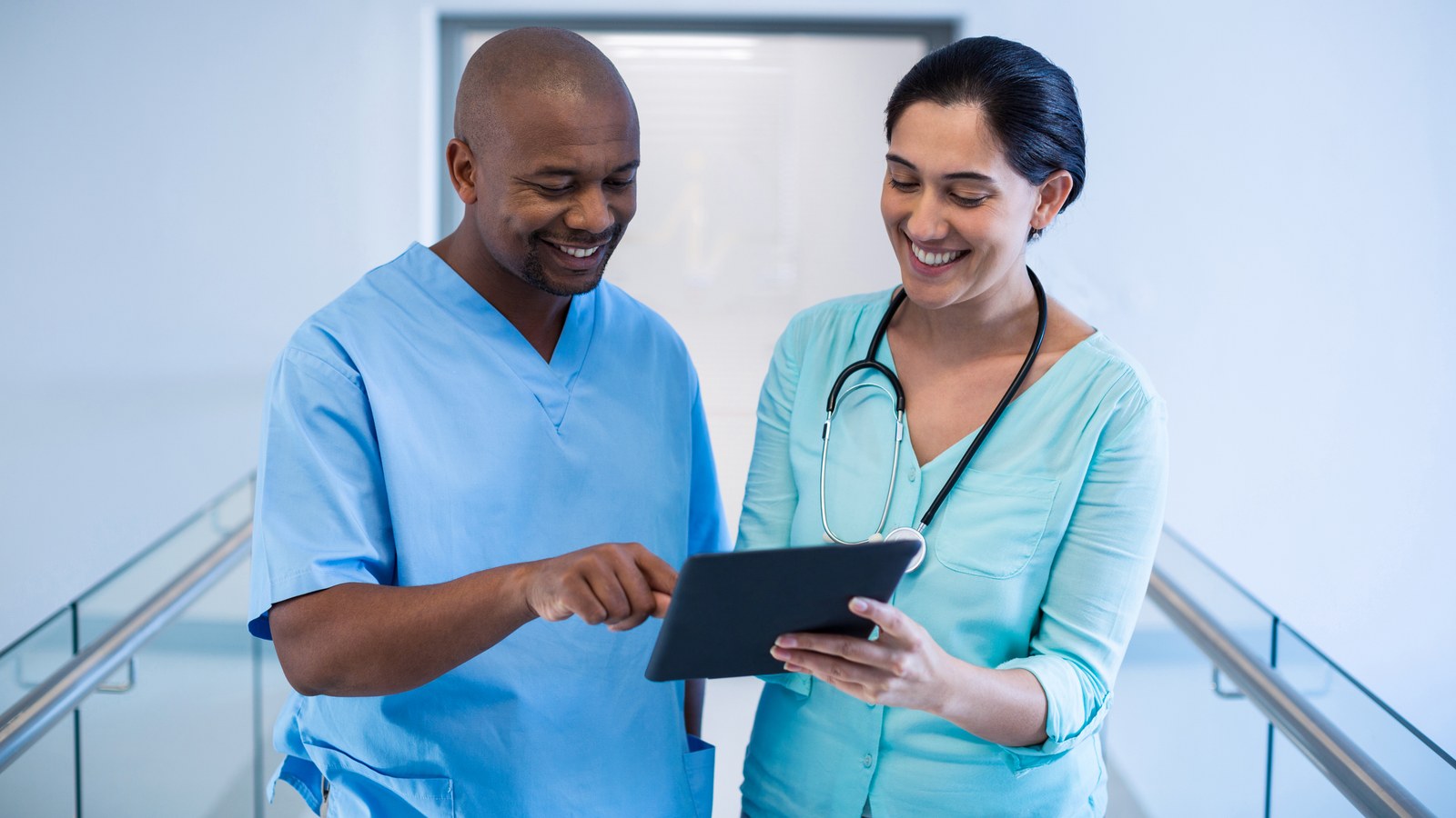Clinicians reviewing patient rounding data together on a tablet."