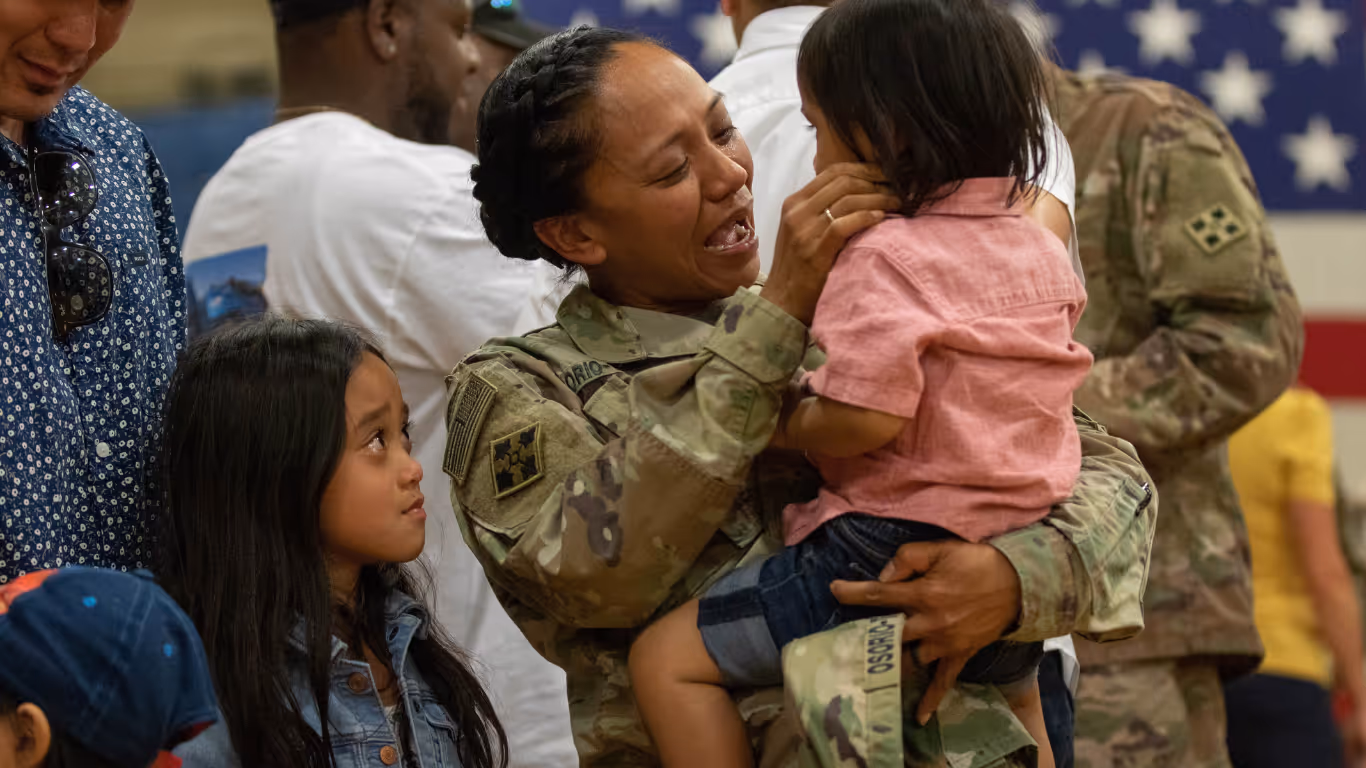 A woman in a military uniform holding a baby.