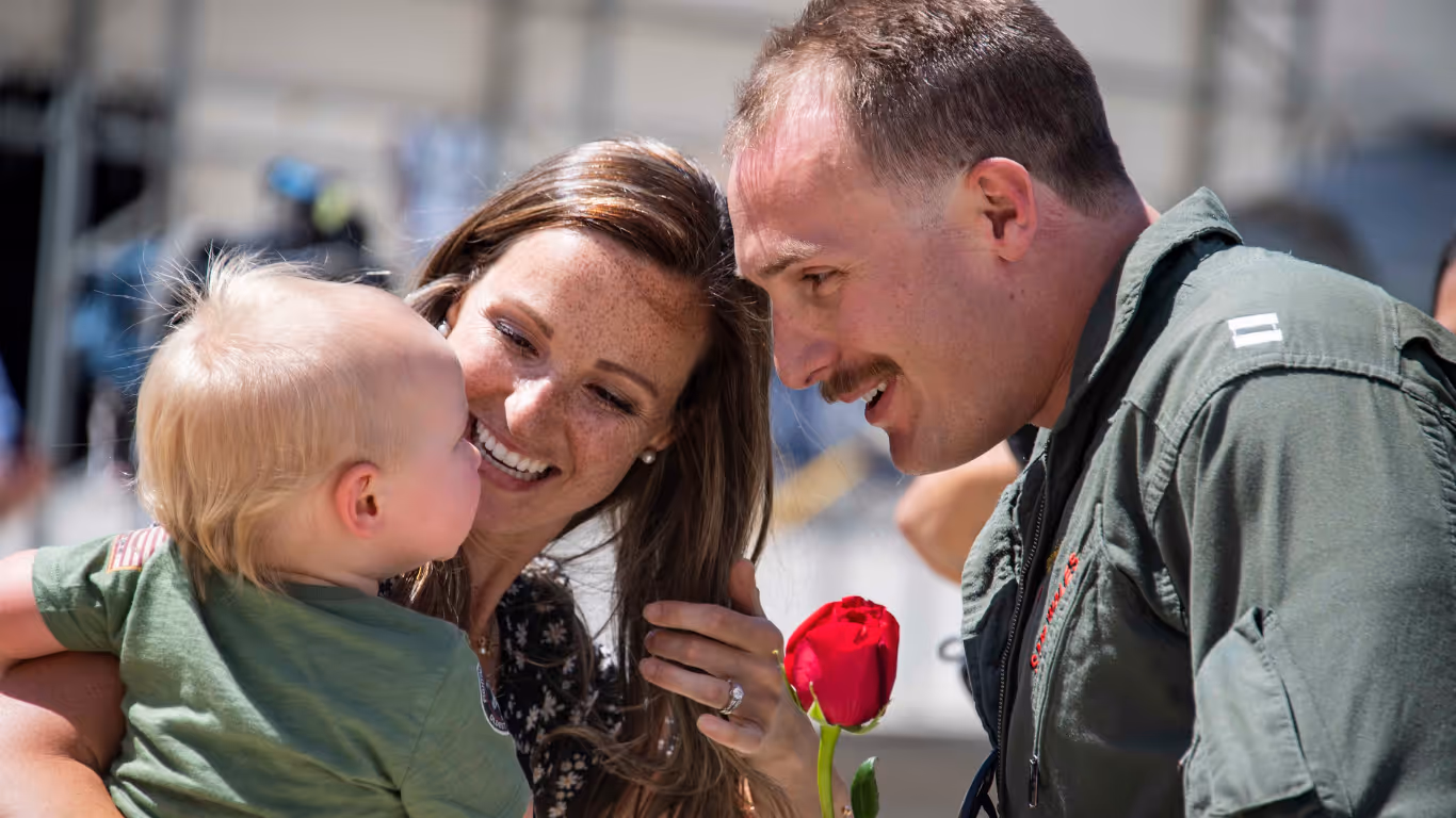 A woman holding a baby and a red rose.