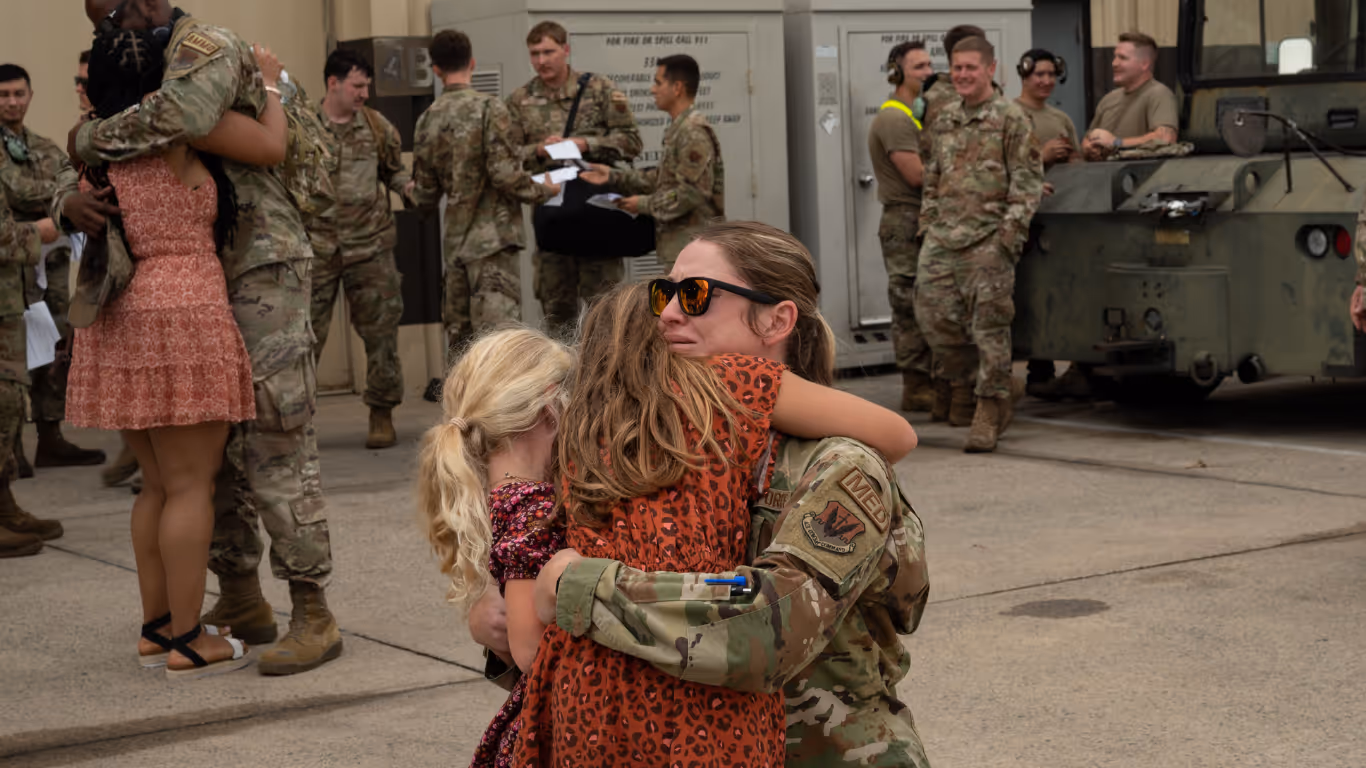 A soldier hugging a woman in a red shirt.