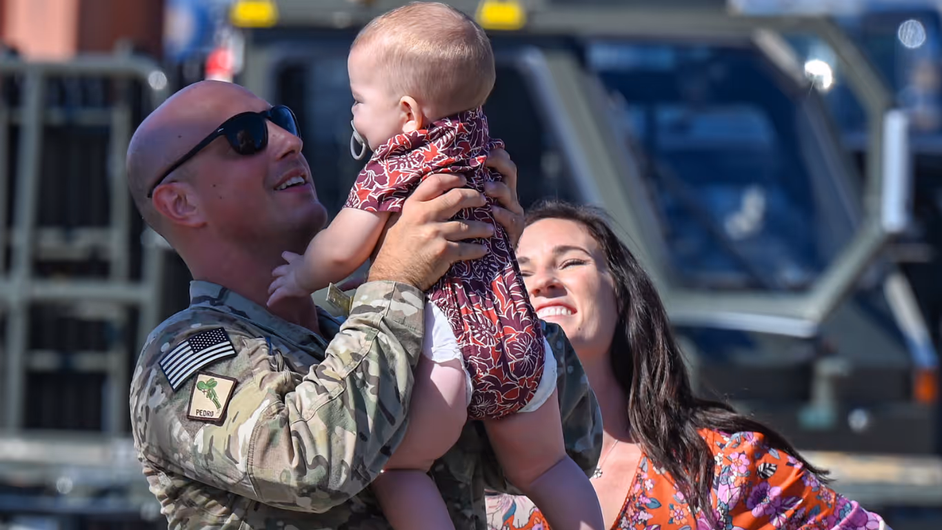 A man in a military uniform holding a baby.